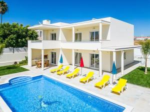 une villa avec une piscine et des chaises jaunes dans l'établissement Villa Vida, à Albufeira