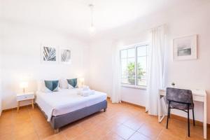 a white bedroom with a bed and a desk at Villa Baya - Great family complex with communal pool in Albufeira
