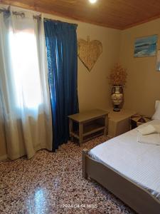 Un dormitorio con una cama y una ventana con cortinas azules. en GIORGOS HOUSE, en Kalambaka