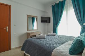 a bedroom with a bed with blue curtains and a window at Basiliki's Apartments in Archangelos