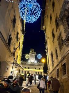 un grupo de personas caminando por una calle con una torre del reloj en La Casa degli Artisti, appartamento centralissimo, en Montepulciano