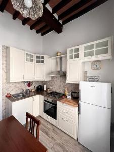 cocina con armarios blancos y nevera blanca en La Casa degli Artisti, appartamento centralissimo, en Montepulciano