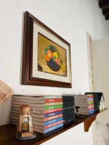 un estante con una pila de libros y una pintura en La Casa degli Artisti, appartamento centralissimo, en Montepulciano