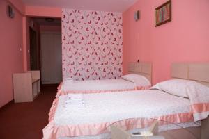 2 Betten in einem Zimmer mit rosa Wänden in der Unterkunft Семеен Хотел Сокол in Sandanski