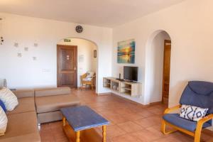 uma sala de estar com um sofá e uma televisão em Villa Primrosa - beautiful sea views em Son Bou