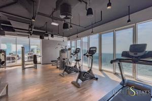 een fitnessruimte met loopbanden en hometrainers in een kamer met ramen bij Luxury Oasis Hideaway in Dubai