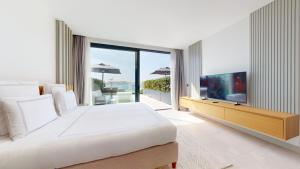 a white bedroom with a large bed and a television at Akana Loft in Bodrum City