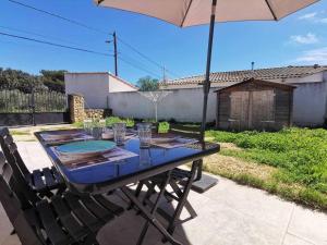 einen Tisch mit Gläsern und einem Regenschirm auf einer Terrasse in der Unterkunft Maison O Volets Bleus Calme Jardin in Miramas