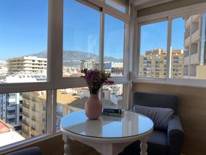 a vase with flowers on a table in front of a window at City & Beach Top-Floor Apartment in Fuengirola
