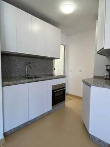a kitchen with white cabinets and a sink and a stove at City & Beach Top-Floor Apartment in Fuengirola +7 photos