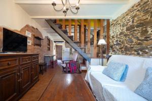 a living room with a couch and a stone wall at La Casona Del Cura II in Pravia