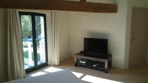 uma sala de estar com televisão e janela em L'Atelier De Dégustation em Vertus