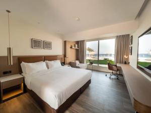 una camera d'albergo con un grande letto e una grande finestra di Luxotel Aqaba Beach Resort & Spa ad Aqaba