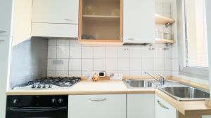 a white kitchen with a sink and a stove at Le Due Farfalle Di Luciana Granella Monica e Deborah Albertin in Chioggia
