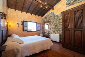 1 dormitorio con cama y pared de piedra en La Casona Del Cura I, en Pravia