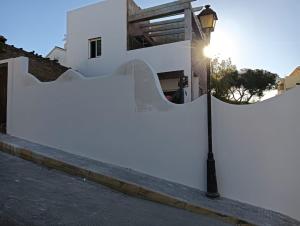 una cerca blanca con un poste de luz al lado de una calle en Alhamar House with private pool, en Punta Umbría