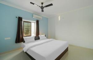 een slaapkamer met een wit bed en een plafondventilator bij Hotel Grace Premium Bhubaneswar Near Khandagiri - Excellent Quality Room - Couple Friendly in Bhubaneshwar