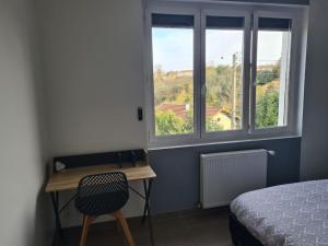ein Schlafzimmer mit einem Schreibtisch und einem Bett und einem Fenster in der Unterkunft Maison rénovée 4 chambres. in Angoulême