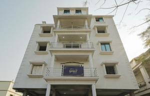 a tall white building with a blue sign on it at Hotel Grace Premium Bhubaneswar in Bhubaneshwar