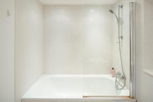 a white bathroom with a shower and a tub at Immaculate 1-Bed Apartment in London in London