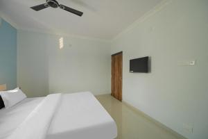 een slaapkamer met een wit bed en een flatscreen-tv bij Hotel Grace Premium Bhubaneswar Near Khandagiri - Excellent Quality Room - Couple Friendly in Bhubaneshwar