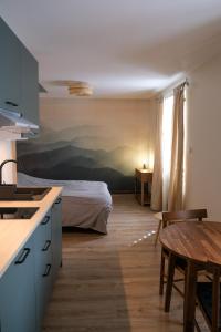 eine Küche mit einem Bett und einem Tisch in einem Zimmer in der Unterkunft Rêverie du Val in Triembach-au-Val