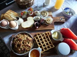 una mesa con productos para el desayuno, huevos y gofres en Chambre poésie, en Froidchapelle