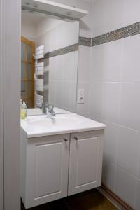 ein weißes Badezimmer mit einem Waschbecken und einem Spiegel in der Unterkunft Rêverie du Val in Triembach-au-Val