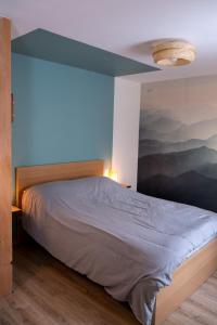 Schlafzimmer mit einem Bett mit blauer Wand in der Unterkunft Rêverie du Val in Triembach-au-Val