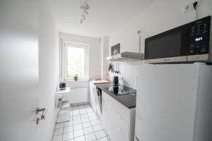 een witte keuken met een koelkast en een raam bij Ferienwohnung Gilla in Leopoldshöhe