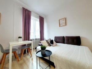 a bedroom with a bed and a table and a desk at Świętojańska Apartament in Gdynia