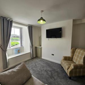 un salon avec un canapé, une télévision et une fenêtre dans l'établissement Bobtail Cottage by Woodland Park, à Staveley