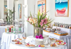 a table with plates of food and a vase of flowers at Miramare E Castello in Ischia
