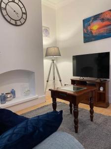 a living room with a table and a clock on the wall at 3 Bedroom Home In Stoke in Stoke on Trent