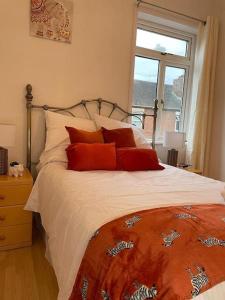 - une chambre avec un lit doté d'oreillers rouges et une fenêtre dans l'établissement 3 Bedroom Home In Stoke, à Stoke-on-Trent