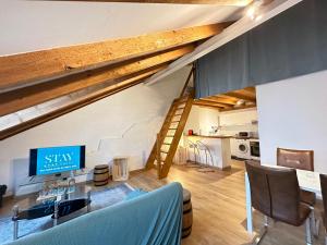 ein Wohnzimmer mit einem Tisch und einem TV im Loft in der Unterkunft Chez Alain Prévu - Boutique Hotel by Stay Swiss in Pruntrut