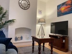 ein Wohnzimmer mit einem TV und einem Tisch mit einer Lampe in der Unterkunft 3 Bedroom Home In Stoke in Stoke on Trent