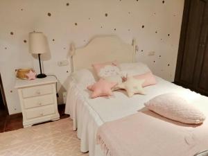 um quarto com uma cama branca e almofadas cor-de-rosa em ALTO DA TORRE em Ilha de Arousa