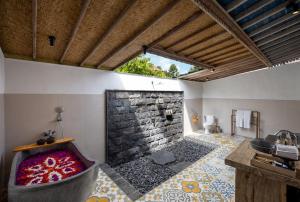 a bathroom with a bath tub and a stone wall at Wooden Ganeca Villas by GenuineHost in Ubud