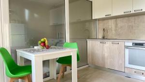 uma cozinha com uma mesa branca e cadeiras verdes em Seafront apartments em Bigovo