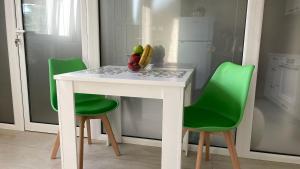 a white table with green chairs in a kitchen at Seafront apartments in Bigovo