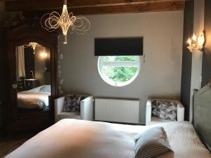 a bedroom with two beds and a window and a chandelier at Logis Hôtel DOMAINE du MOULIN in Saint-Avold