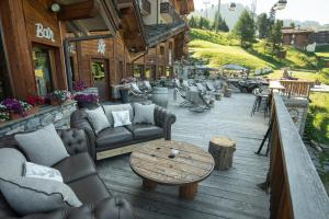 une terrasse en bois avec des canapés et des tables. dans l'établissement Hôtel Carlina by Les Etincelles, à Belle Plagne