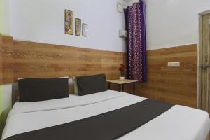 1 dormitorio con 1 cama y pared de madera en OYO Anand Villa en Nueva Delhi