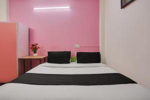 Cama en habitación con pared de color rosa en OYO Anand Villa en Nueva Delhi