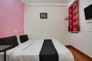1 dormitorio con 1 cama y TV en la pared en OYO Anand Villa en Nueva Delhi