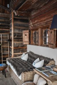 a bedroom with a couch and wooden walls at House of Hütter - Wachtelhof Hotel & Spa in Maria Alm am Steinernen Meer