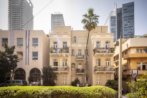 um edifício com uma palmeira em frente a edifícios altos em Bauhaus Artistic Haven in the Heart of Tel Aviv by Sea N' Rent em Tel Aviv