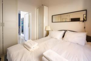 a white bed with white pillows and a mirror at Bauhaus Artistic Haven in the Heart of Tel Aviv by Sea N' Rent in Tel Aviv