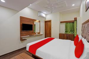 1 dormitorio con 1 cama grande y TV en OYO Flagship Hotel Swagat Inn, en Ahmedabad